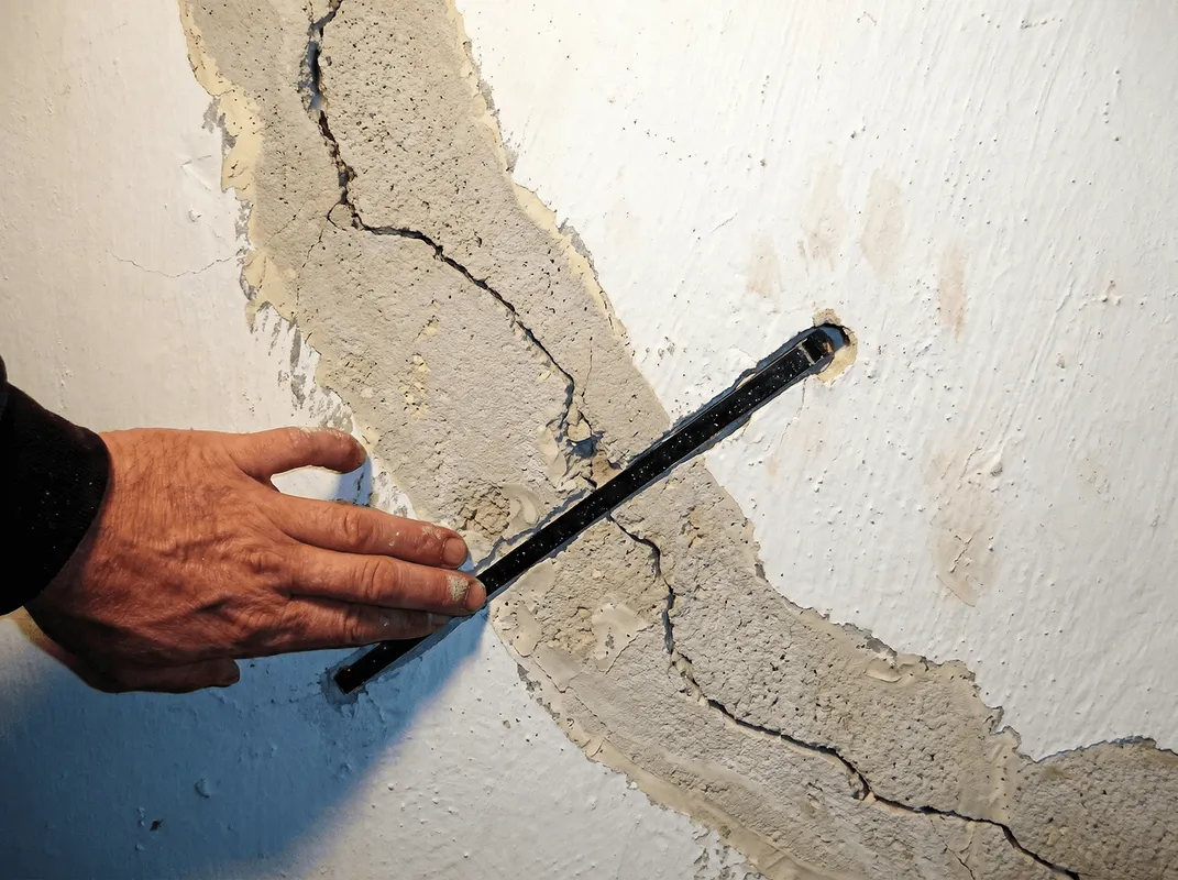 A wall with a large crack is being inspected by a professional in Madison, WI